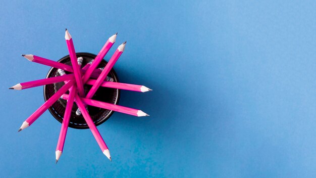 Pink pencils in the holder against blue background