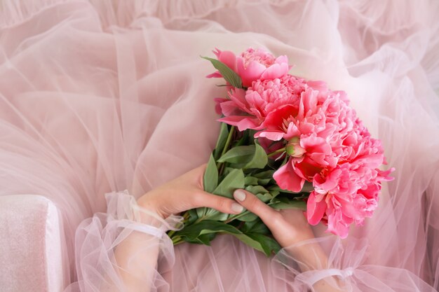 女性の手でピンクの牡丹の花の花束