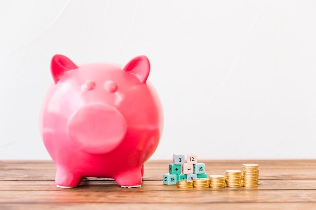 Free photo pink piggybank near stacked coins and math blocks