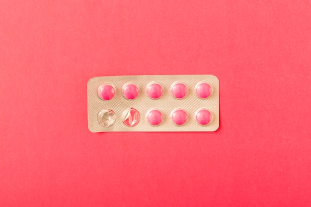 Pink pills blister over the dark background