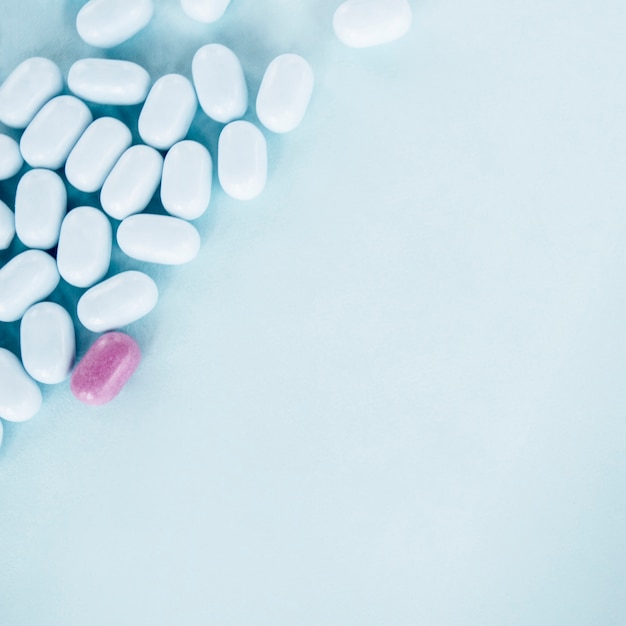 Pink pills with white tablets over the blue background