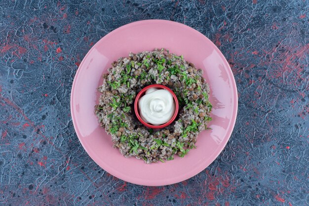 A pink plate of mincemeat with peas and herbs 