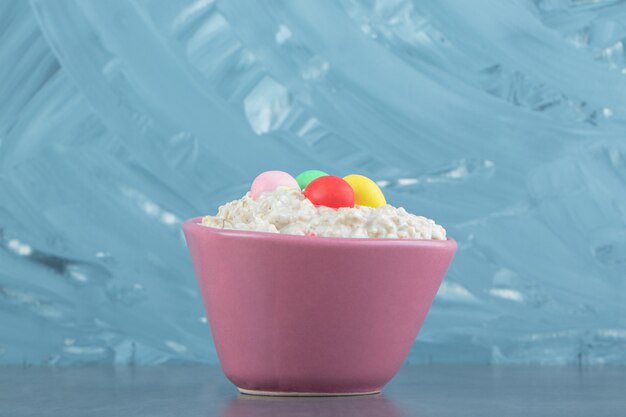 A pink plate of oatmeal porridge with colorful candies .