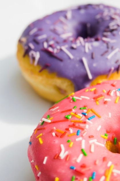 Pink and purple donuts with colorful sprinkle on white backdrop