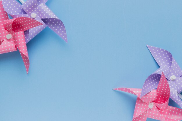 Pink and purple polka dotted pinwheel arrange at the corner of blue backdrop