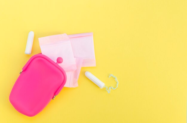 포장 된 생리대와 탐폰이있는 핑크색 지갑