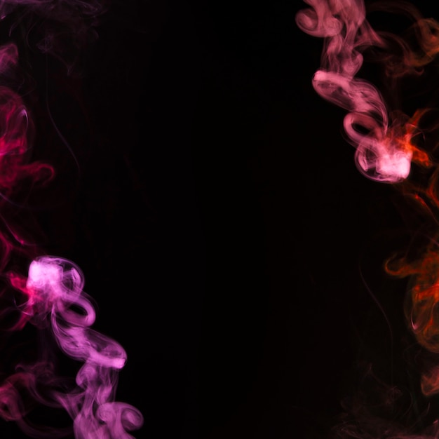 Free photo pink and red plume of smoke becoming wavy swirls on black background