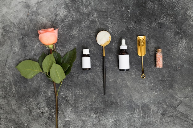 Pink rose flower; essential oils and himalayan rock salt on black textured backdrop