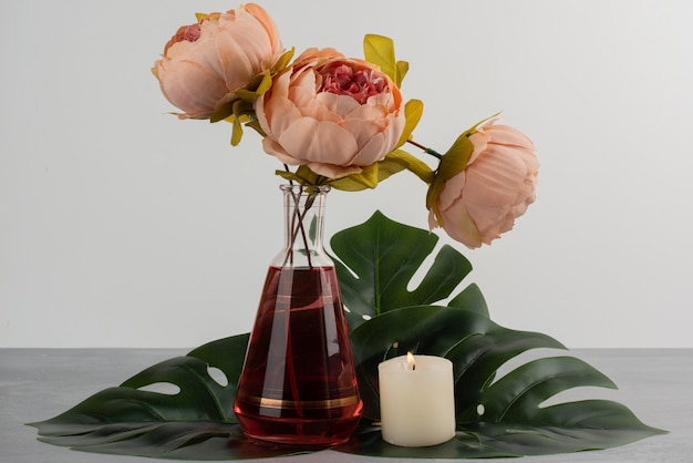 Fiori di rosa rosa in vaso di vetro e candela