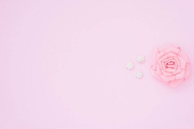 Pink rose made with ribbon on pink background with space for writing the text
