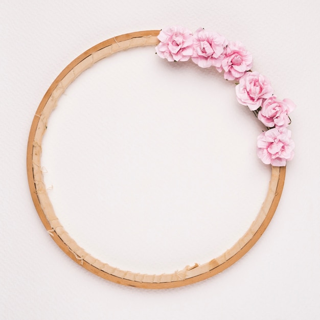 白い背景に円形の木製フレームに飾られたピンクのバラ