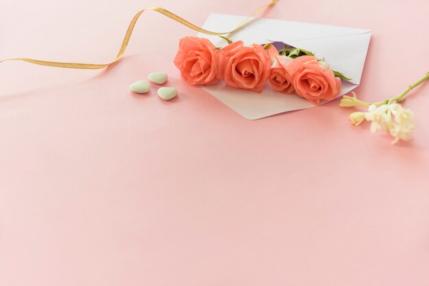Pink roses in envelope with hearts on table