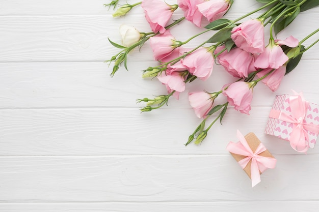 Pink roses and gifts boxes on wooden background