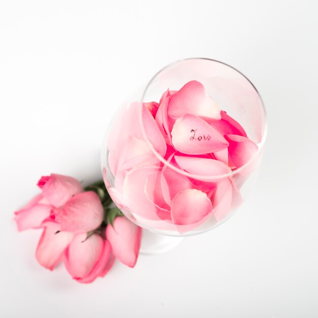 Pink roses petals in glass on table 