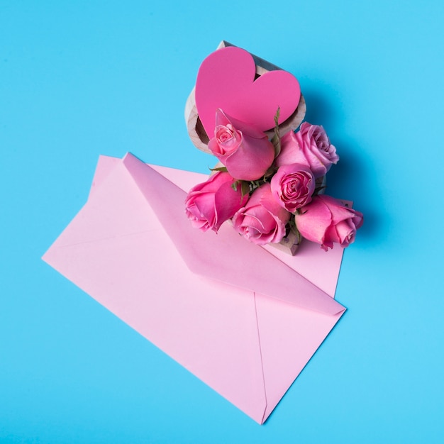 Pink roses with envelope on table 