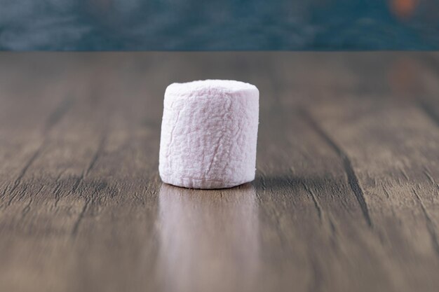 Pink round marshmallow on wooden ground.