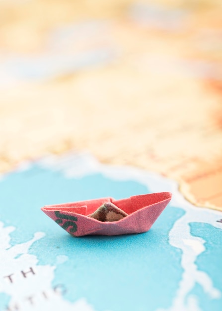 Розовая маленькая лодка на карте мира