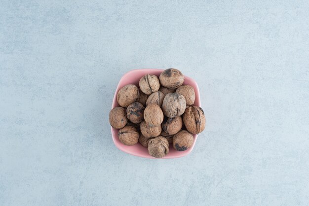 大理石の背景にナッツでいっぱいのピンクの小皿。高品質の写真