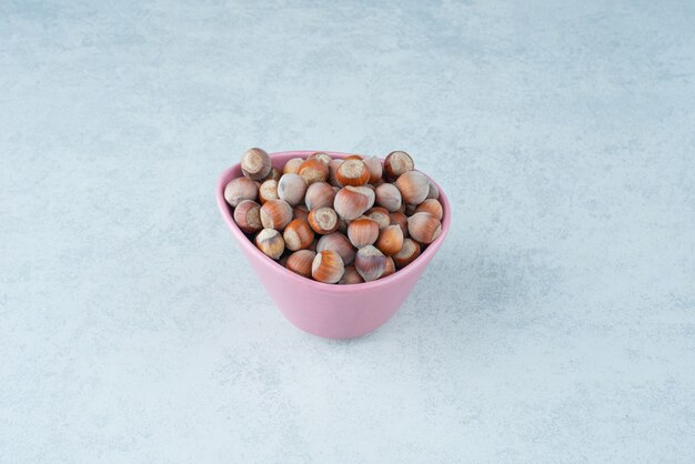 A pink small plate full of nuts on marble background. High quality photo