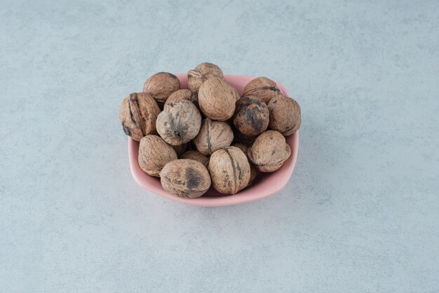 A pink small plate full of nuts on marble background. High quality photo