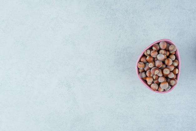 A pink small plate full of nuts on marble background. High quality photo