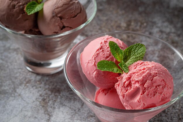 Шарики розового клубничного и шоколадного мороженого в чашке на сером каменном столе