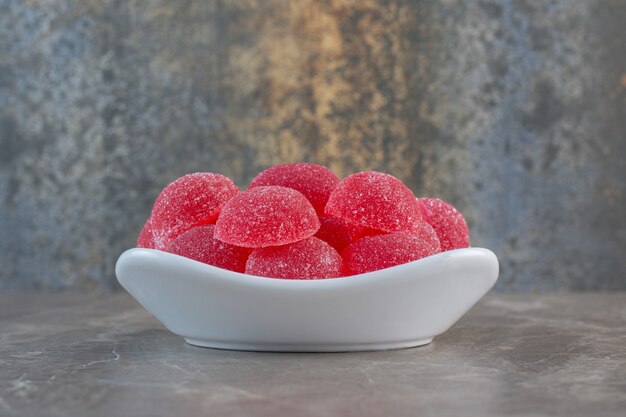 Pink strawberry candies in white ceramic bowl.