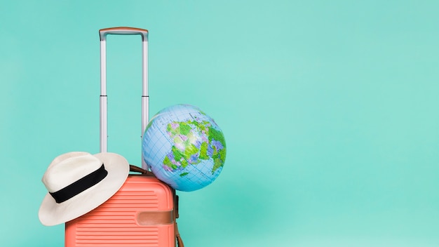 Pink suitcase with hat and globe on it