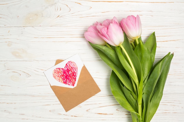 Pink tulip flowers with heart drawing in envelope 