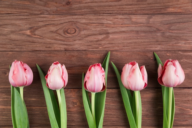 Free photo pink tulips on wooden textured background