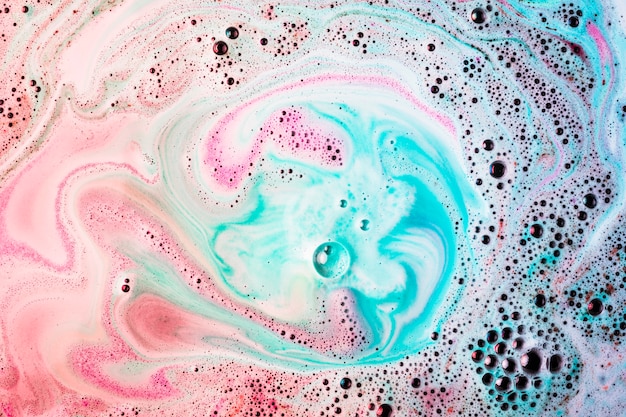Pink and turquoise bath bomb dissolving in water