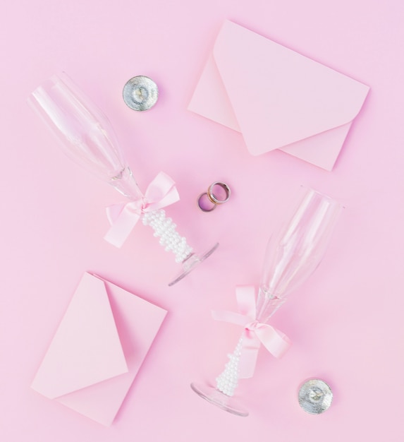 Бесплатное фото Розовая свадебная композиция с бокалами для шампанского и приглашениями