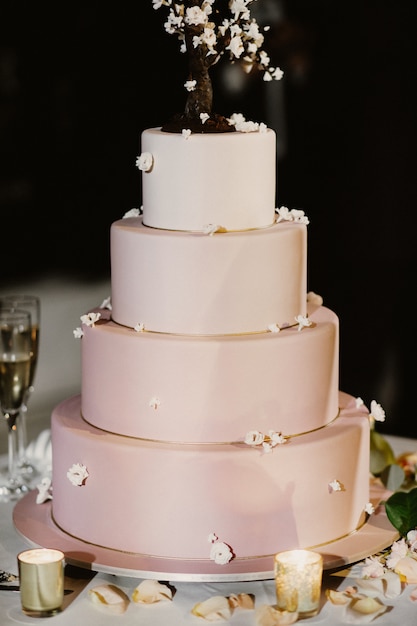 Pink wedding cake decorated with candles and rose petals