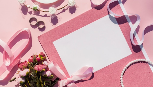 Pink wedding invitation next to wedding items