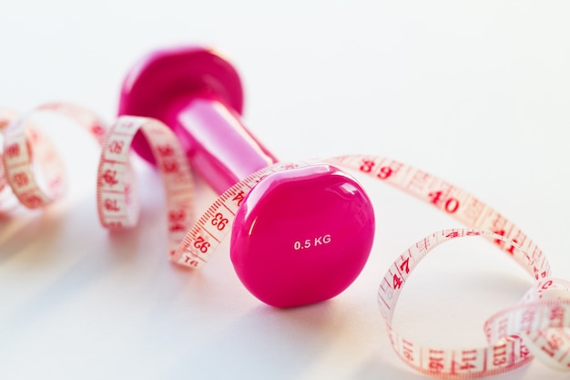 Free photo pink weights and a tape measure