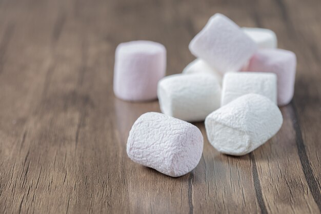 Pink and white fluffy marshmallows on a wooden board.