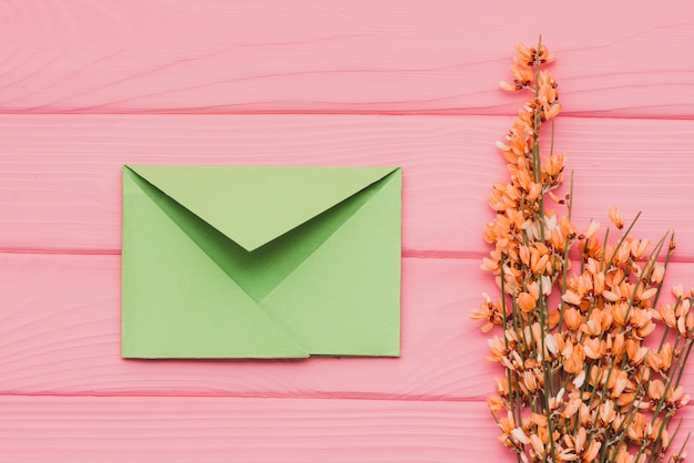 無料写真 緑色の封筒と花飾りのついたピンクの木製の表面