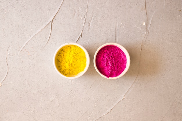 Free photo pink and yellow color powder in the white bowls on backdrop