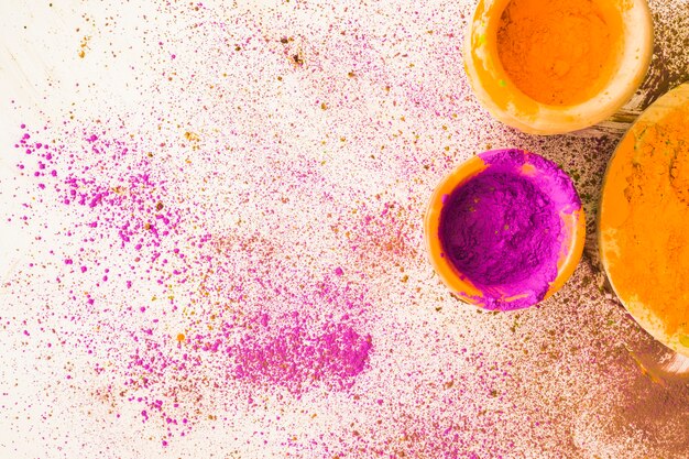 Pink and yellow holi powder bowl with stained on white background