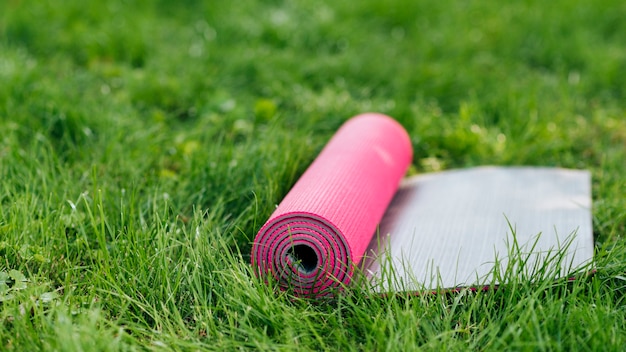 Foto gratuita stuoia rosa di yoga su erba