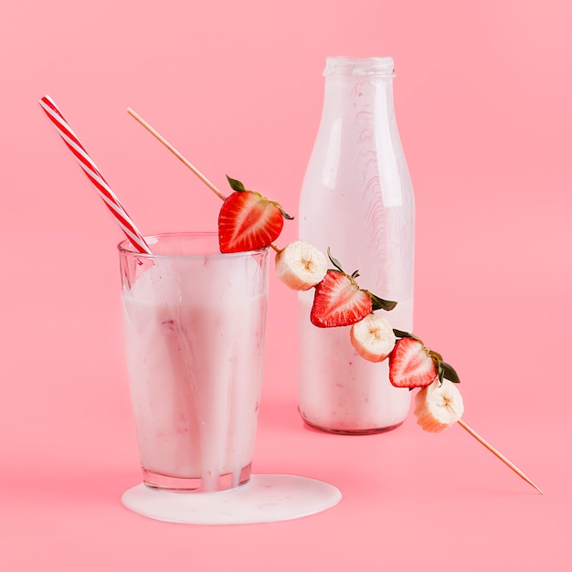 Розовый йогурт в бутылке и стакан с ягодами