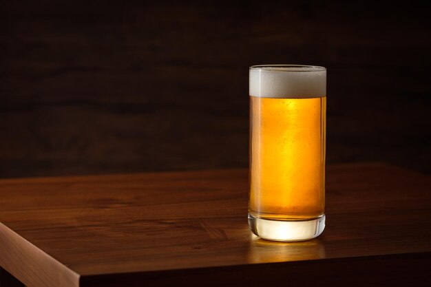 Pint glass of beer with a foam on wooden table
