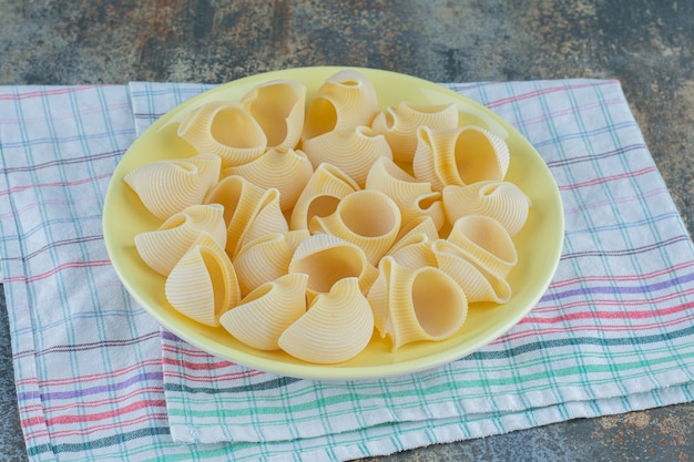 Foto gratuita pipe rigate nella ciotola, sul tovagliolo sullo sfondo di marmo.