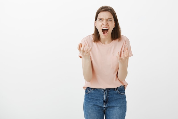 Pissed-off angry woman clenching hands and looking mad at someone, shouting hateful