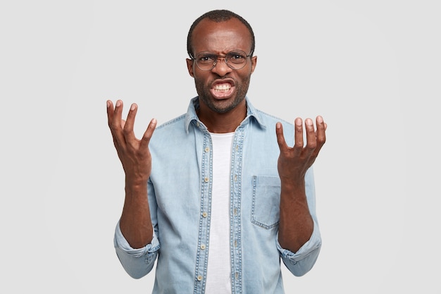 Free photo pissed off annoyed black man screams and shakes palms, fed up of arguing, clenches teeth