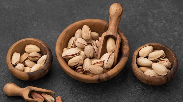 Pistachio nuts in bowls with wooden spoons