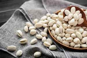 Free photo pistachios in a wooden spoon. wooden bowl with nut pistachios. on a wooden background, near a bag from burlap. healthy food and snack, organic vegetarian food.