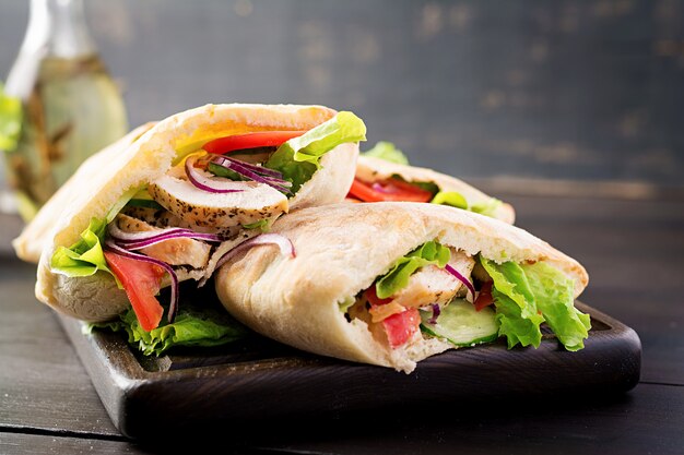 Pita stuffed with chicken, tomato and lettuce on wooden table. Middle Eastern cuisine.