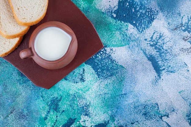 A pitcher of fresh milk with sliced white bread on a brown tray .