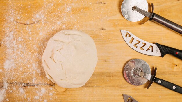 Pizza cutters and knives near dough